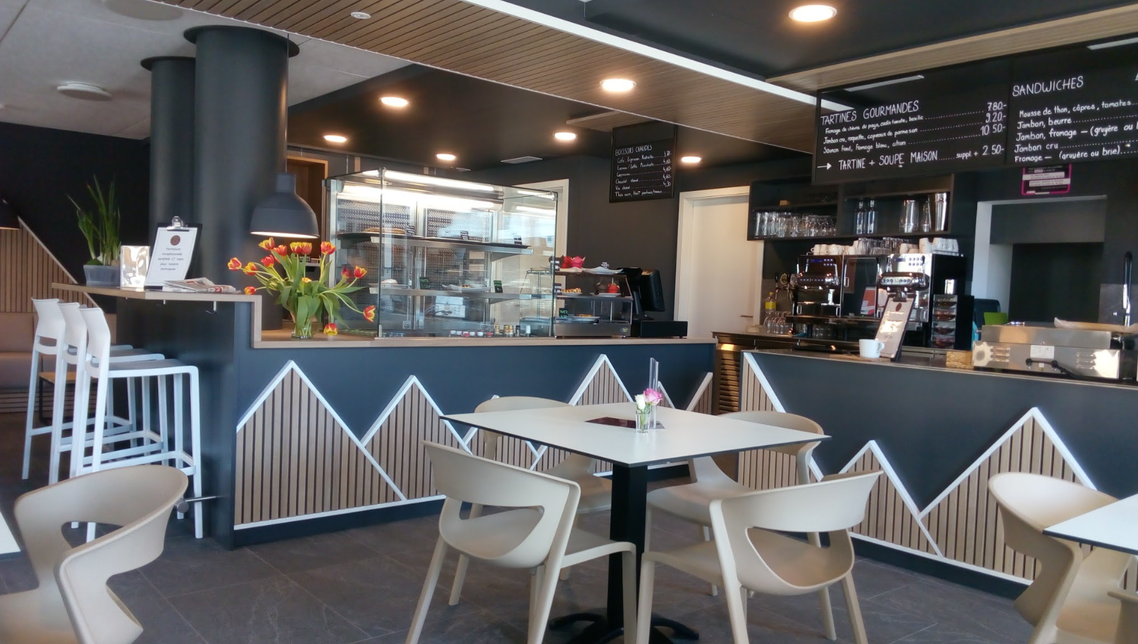 Intérieur du Café La Randonnée, avec ses tables et son comptoir décoré de montagnes